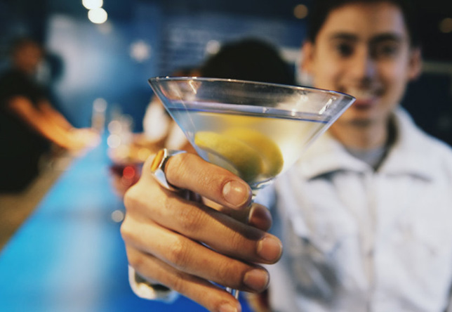 A man holding out a boring drink at a bar